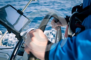 Hands of the skipper at the helm control of sailing boat