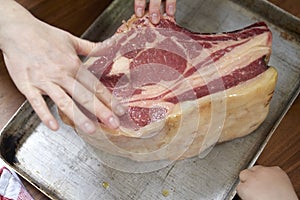 Hands on Slab of Raw Beef Cut on Tray