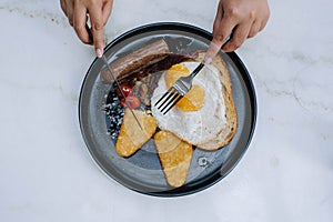 Hands slicing the sourdough on a plate of full english fry up breakfast menu