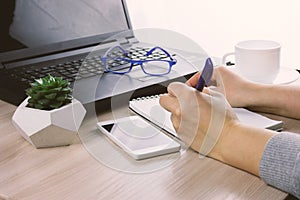 Hands with smartphone on a bsckground of working place with laptop,succulent and coffee cup