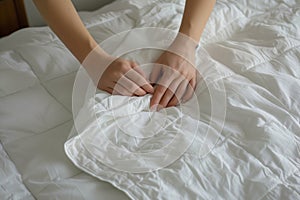 hands smoothing a white duvet on a kingsize bed photo