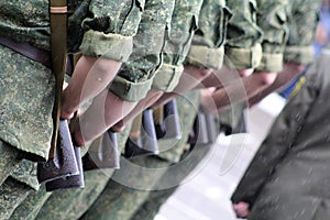 the hands of soldiers and their weapons in green uniforms in formation