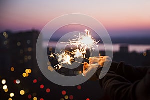 Hands with sparkles Bengal fire  that bokeh cities background.