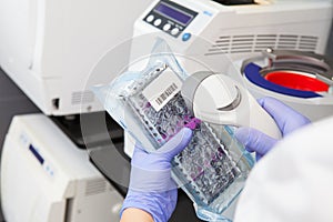 Hands specialist in gloves scans sterile dental instruments