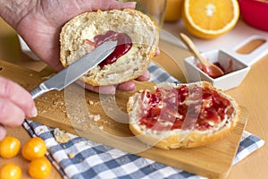 Hands spread half a bun with jam