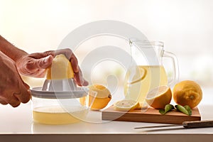 Hands squeezing a lemon on kitchen bench front view