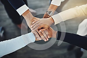 Hands stacked or piled to show team unity, strength or motivation among business men, women or colleagues from above