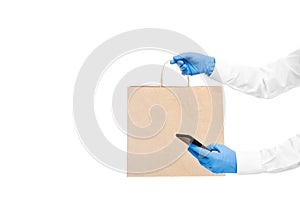 Hands in sterile gloves of a courier for safe food delivery of an online order by cell phone.