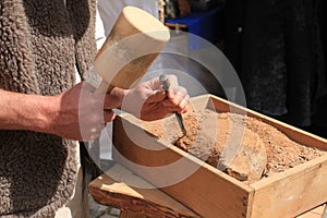Hands of a stonemason with hammer and chisel at work