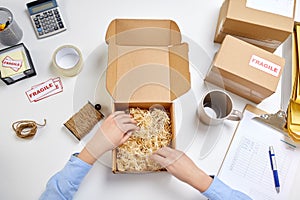 Hands with straw filler in parcel at post office