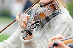 Hands of a street musician girl with violin close up