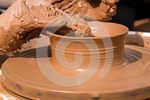 Hands of a street potter make a clay pot on a potter`s wheel.