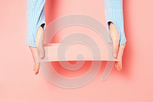 Hands stretching fitness elastic band on pink background close-up.