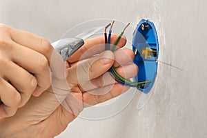 Hands striping the insulation of wires with cutter