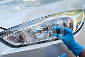 Hands of strong man mechanic hold halogen car lamps against headlights and repair car.