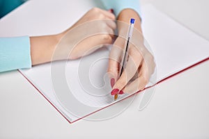 Hands of student girl with pen writing to notebook