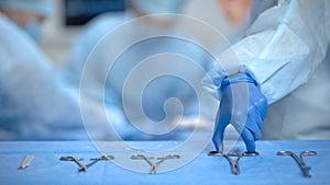 Hands of surgeon assistant taking sterile medical equipment from table, clinic