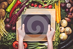 Hands with Tablet over Fresh Organic Vegetables Background