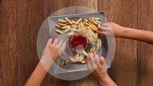 Hands taking french fries from a rotating plate