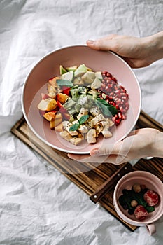 Hands taking fresh fruits on a pink bowl. Healthy food, breakfast in bed.