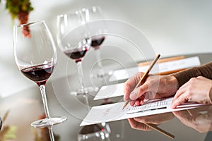 Hands taking notes at wine tasting.