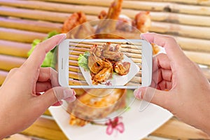 Hands taking photo chicken wings with smartphone