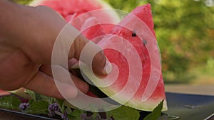 Hands taking red watermelon slices from a plate