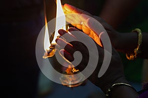 Hands taking warmth of Divine diya holy flame of hindu god worship puja for blessings