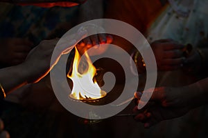 Hands taking warmth of Divine diya holy flame of hindu god worship puja for blessings
