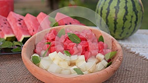 Hands taking watermelon and musk-melon cubes from a plate. Summer refreshing fruit salad close up
