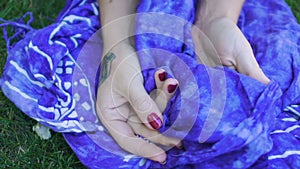 Hands with tattoos hold silk veil women's fingers crumple blue cover slow motion