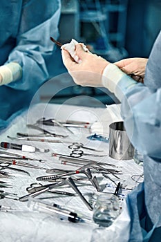 Hands of a team of surgeons close-up in the operating room during the operation, sterile instruments are laid out on the