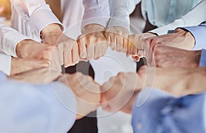 Hands, teamwork and motivation with a team of business people joining their fists in a huddle or circle.