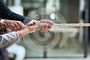 Hands, teamwork and rope with business people pulling during a game of tug of war in the office. Collaboration, help and