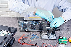 Hands of a technician repairing a broken laptop computer