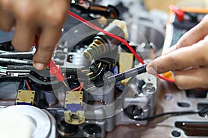 Hands of a technician using a multimeter to check the wiring and solenoid