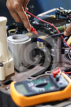 Hands of a technician using a multimeter to check the wiring and solenoid
