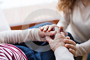 Hands of teenage girl and her grandmother at home.