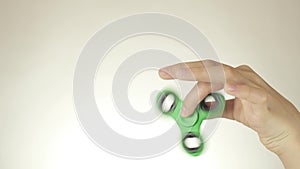 Hands of a teenage girl spin a green fidget spinner on white background stock footage video