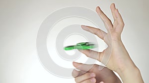 Hands of a teenage girl spin a green fidget spinner on white background stock footage video