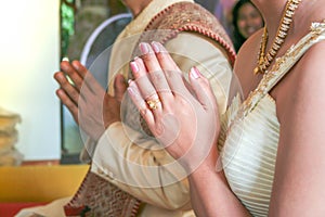 Hands of Thai groom and bride pray to the monk