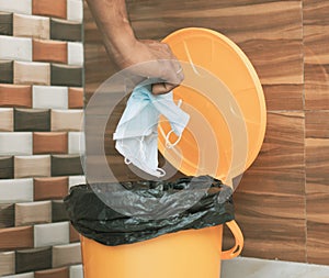 Hands throwing medical mask into closed bin - Covid-19, Coronavirus advice to discard or dispose medical mask to closed