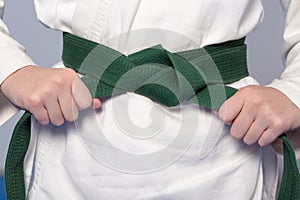 Hands tightening green belt on a teenage dressed in kimono