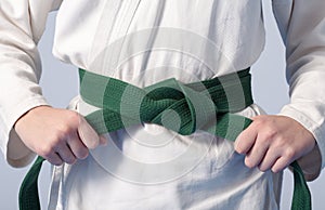 Hands tightening green belt on a teenage dressed