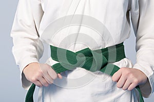 Hands tightening green belt on a teenage dressed in kimono