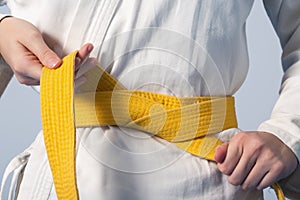 Hands tightening yellow belt on a teenage dressed