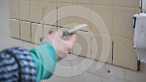 Hands of tile worker filling gaps between tiles with grout