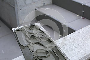 The hands of the tiler are laying the ceramic tile on the floor.