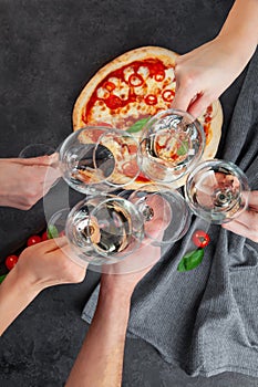 Hands together with glasses of white wine on background pizza