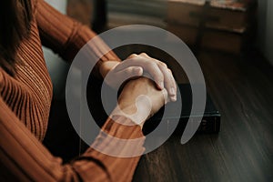 Hands together in prayer to God along with the bible In the Christian concept and religion, woman pray in the Bible on the table